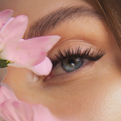 Olho feminino com pestanas longas e pétalas de flores cor de rosa