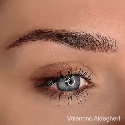 Close-up de um olho azul com sobrancelha castanha e pestanas longas