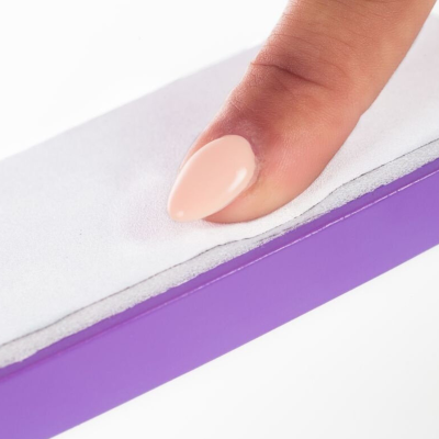 Unha artificial rosa claro em mão sobre lixa de unhas branca com base roxa