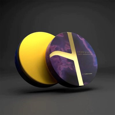 Embalagem redonda preta e roxa com tampa aberta mostrando conteúdo amarelo