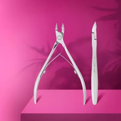 Ferramentas para manicure em metal prateado sobre fundo rosa