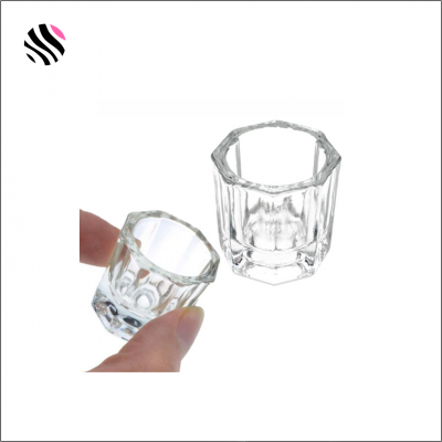 Dois copos de vidro facetados transparentes, um segurado por uma mão