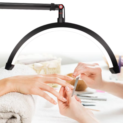 Lâmpada circular preta com braço articulado sobre mesa de manicure com pessoa a limar unhas.