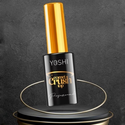 Frasco de verniz para unhas YOSHI Comet Crush top preto e dourado sobre suporte preto com anéis dourados