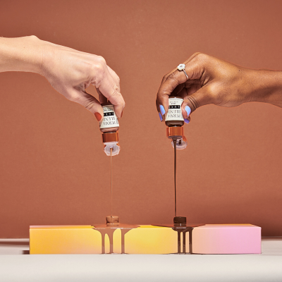 Duas mãos a derramar tinta acrílica castanha e preta sobre blocos coloridos