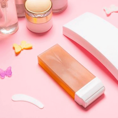 Produto de depilação com cera quente e acessórios em superfície rosa