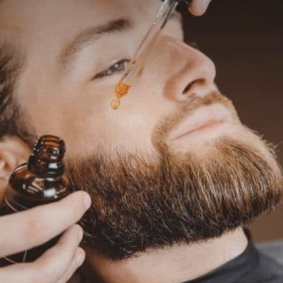 Homem a aplicar óleo para barba com conta-gotas