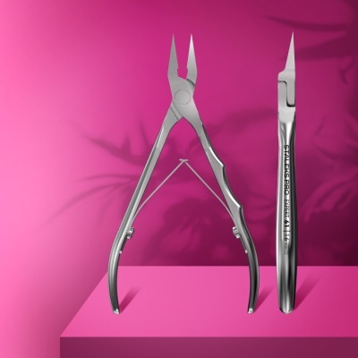 Utensílios de manicure em metal prateado sobre pedestal cor-de-rosa