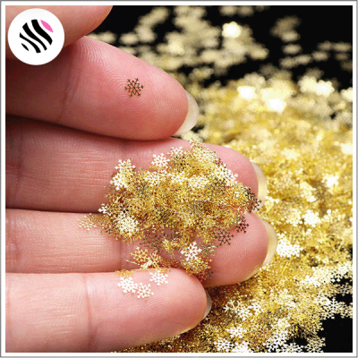 Mão segurando pequenos flocos de neve metálicos dourados