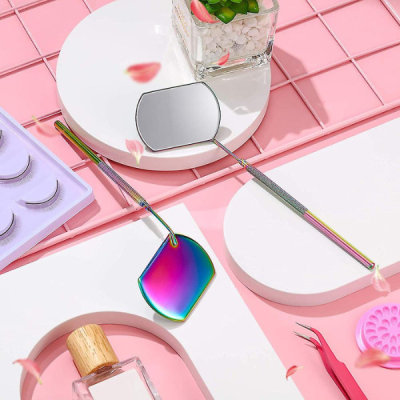 Espelho dental colorido em tons iridescentes com acessórios sobre fundo cor-de-rosa