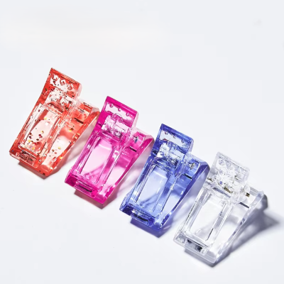 Quatro ganchos de cabelo em acrílico colorido com glitter, nas cores laranja, rosa, azul e transparente, alinhados.