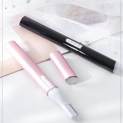 Dois depiladores elétricos, um preto e um rosa, sobre superfície branca com tecido translúcido e estrelas douradas.