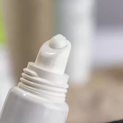 Frasco branco com aplicador de rolo contendo creme branco