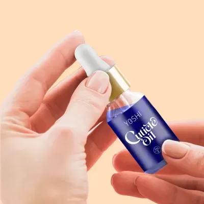 Frasco de óleo para cutículas YOSHI com conta-gotas nas mãos femininas
