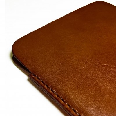 Carteira de pele castanha com costura visível sobre fundo branco