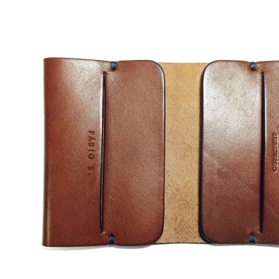 Carteira de pele castanha clara aberta com inscrições no interior