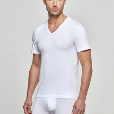 Homem com camisola interior branca de algodão e cuecas boxer brancas em fundo cinzento claro.