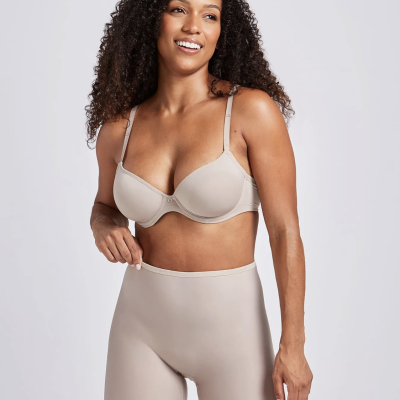 Mulher com roupas interiores bege em fundo branco