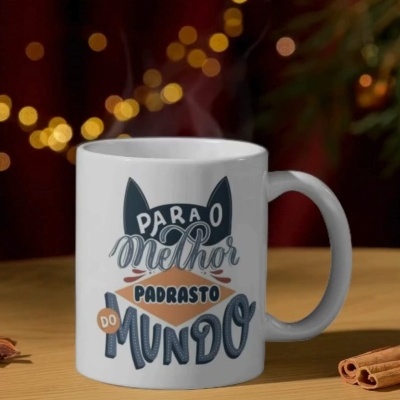 Caneca branca com texto decorativo em várias cores sobre superfície de madeira e paus de canela