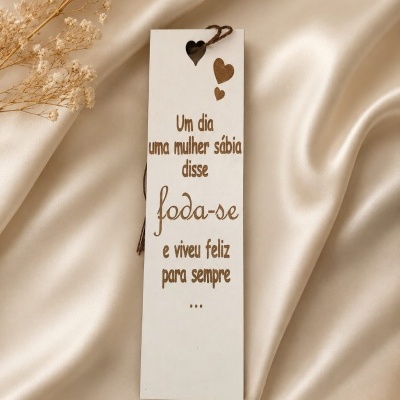 Marcador de livros branco com texto gravado e corações sobre tecido creme brilhante e flores secas.