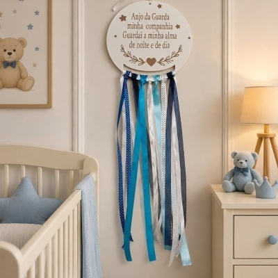 Decoração de parede com texto e fitas penduradas num quarto de bebé com berço e ursinho azul