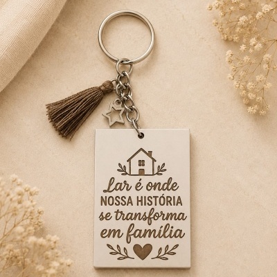 Porta-chaves metálico com frase gravada, borla castanha e pendente estrela, em fundo bege com flores secas