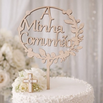 Topo de bolo em madeira com texto A Minha Comunhão e bolo branco decorado com flores e biscoito em forma de cruz.