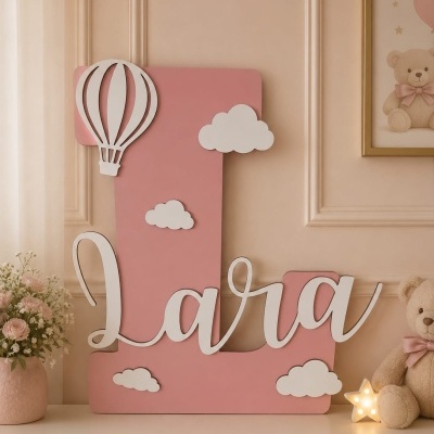 Letra decorativa rosa com nome Lara em branco, nuvens e balão em branco, ao lado de urso de peluche e luminária de estrela