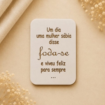 Placa decorativa branca com texto recortado sobre fundo bege e flores secas.