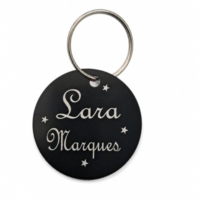 Chaveiro redondo preto personalizado com o nome Lara Marques e estrelas brancas.