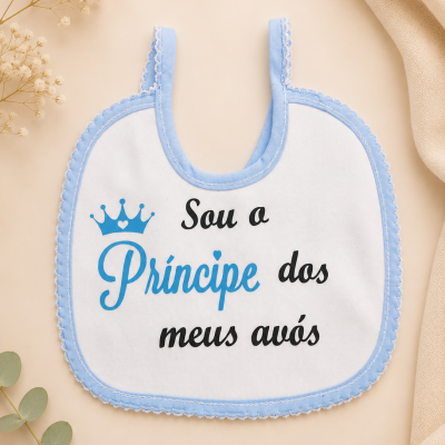 Babete branco com bordas azuis e texto colorido sobre fundo bege com flores e folhas.