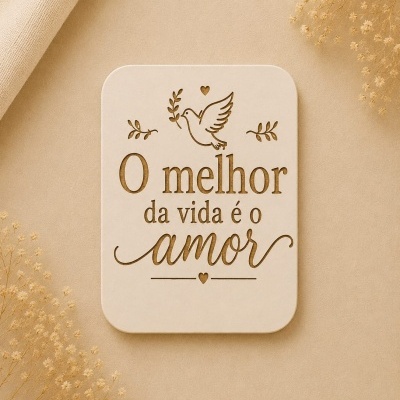 Placa decorativa em madeira clara com texto de amor e pomba, rodeada de flores secas sobre fundo bege.