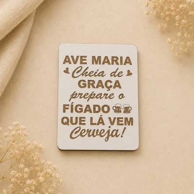 Placa retangular branca com texto humorístico e decoração de corações e copos de cerveja em fundo bege com ramos secos