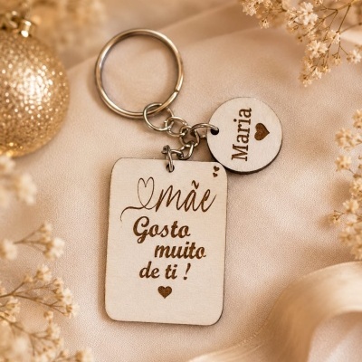 Porta-chaves em madeira gravado com o nome Maria e texto para mãe sobre tecido bege com flores e ornamento.