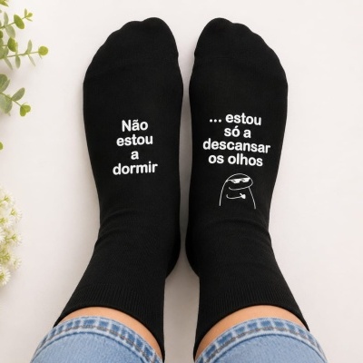 Meias pretas com texto branco e personagem desenhada, usadas, com plantas ao lado