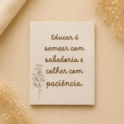 Placa decorativa em tecido branco com texto motivacional e ilustração de flores sobre fundo bege.