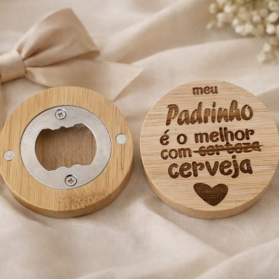 Abridor de garrafas em madeira com gravação para padrinho sobre tecido bege.