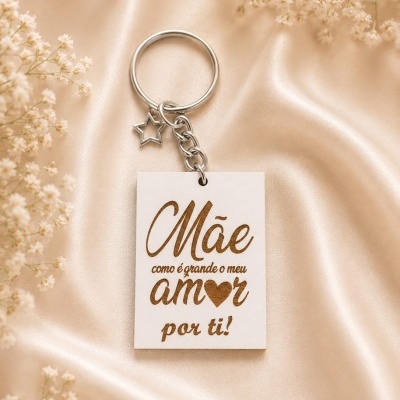 Chaveiro metálico com pendente branco e frase gravada sobre tecido acetinado