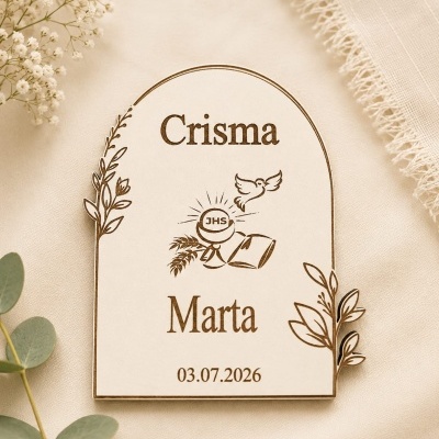 Placa de madeira clara para Crisma com texto, motivos religiosos e elementos naturais gravados, sobre tecido bege com flores e folhas.