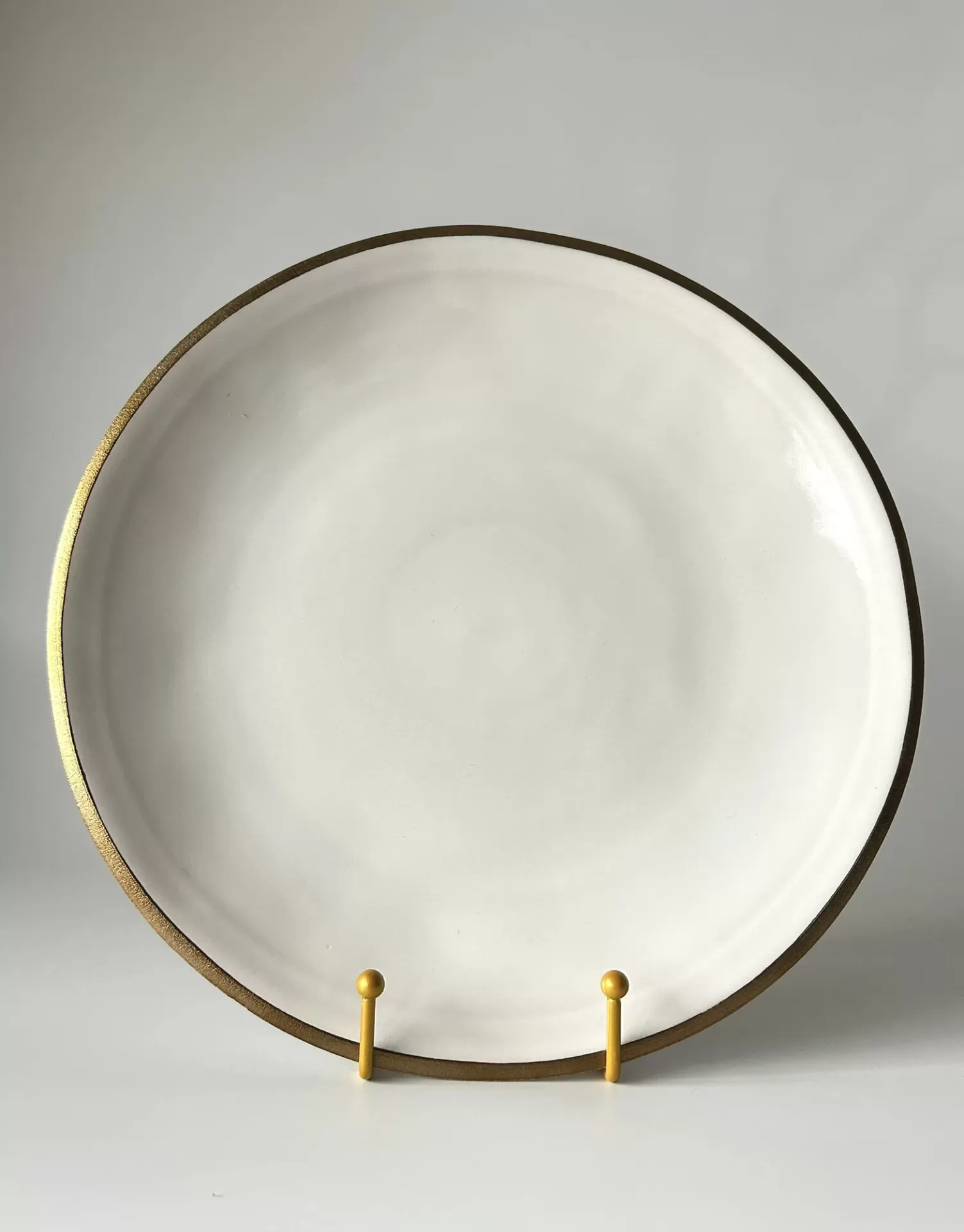 Prato cerâmico branco com borda dourada numa base amarela