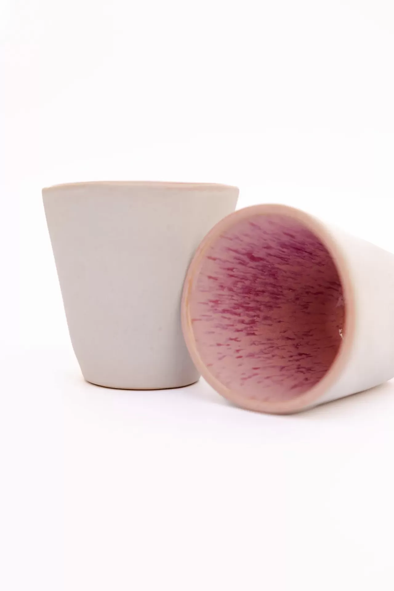 Duas chávenas cerâmicas branca e rosa sobre fundo branco