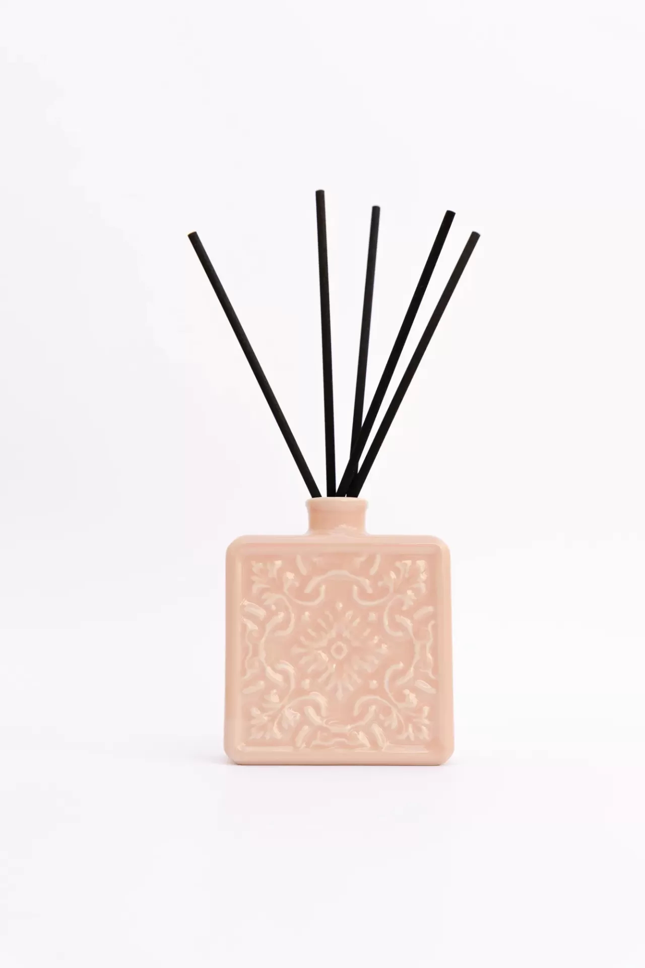 Difusor de aromas cerâmico cor-de-rosa com varetas pretas.
