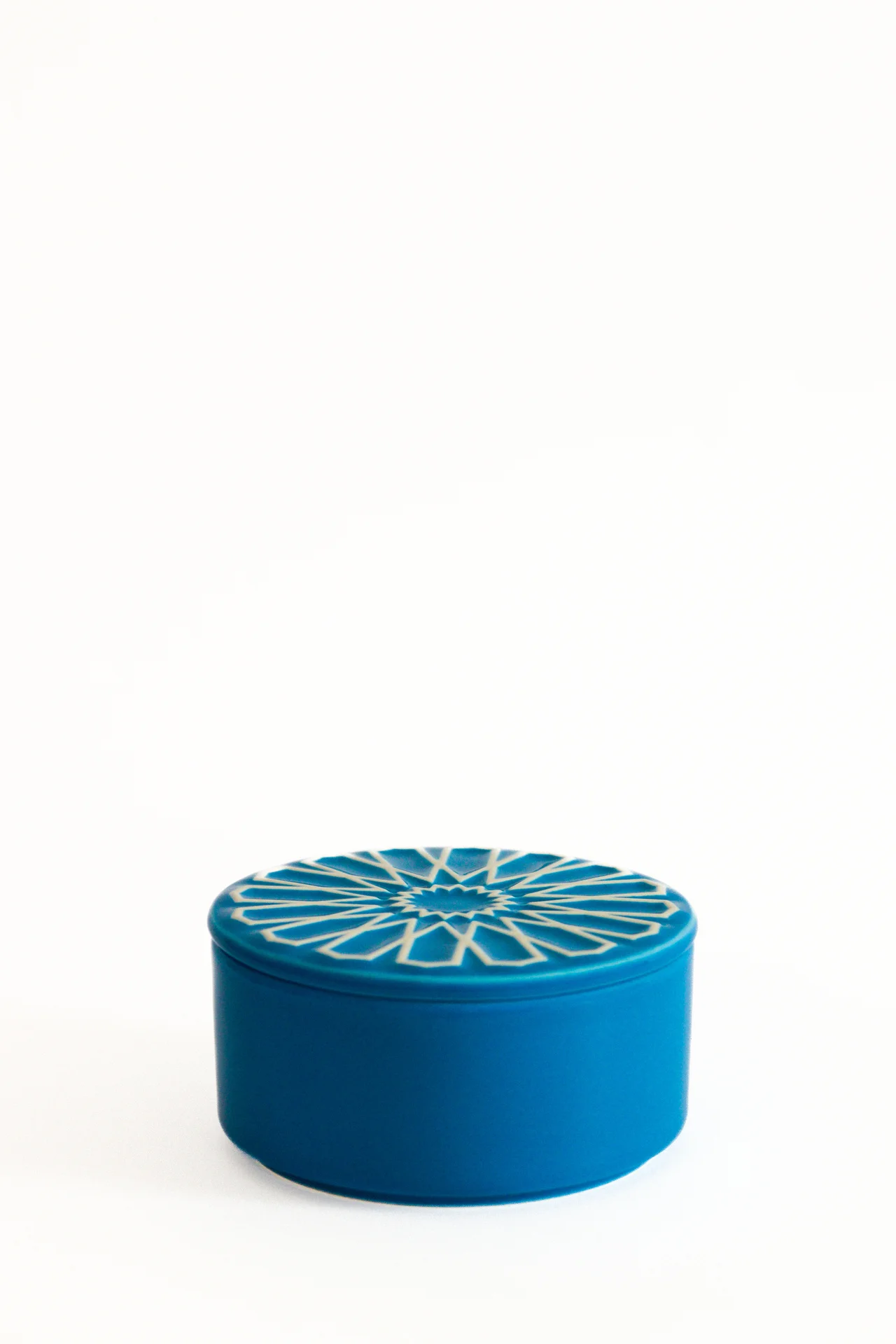 Caixa cerâmica azul com padrão geométrico branco no tampo