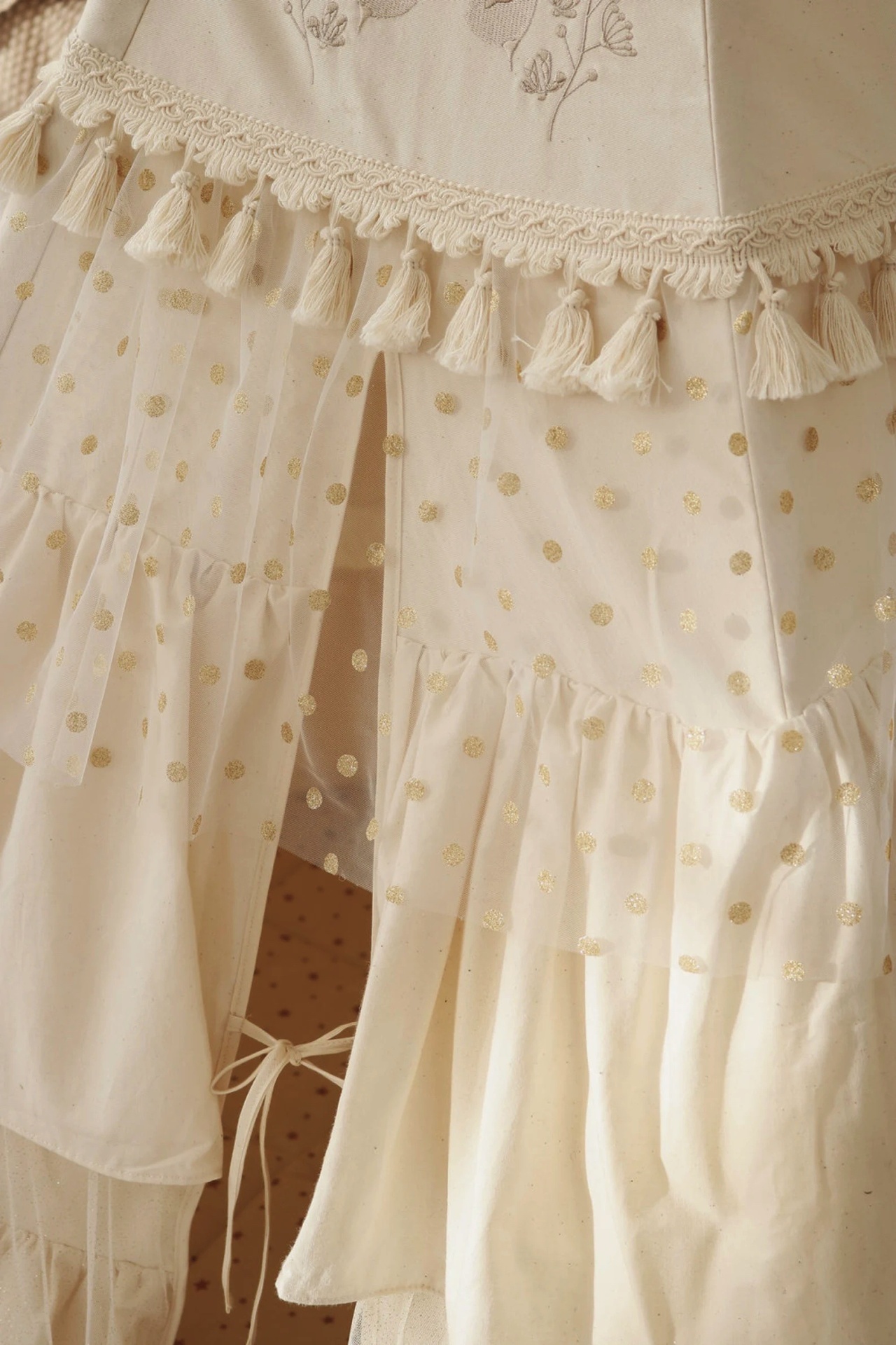 Vestido infantil branco com bolinhas douradas e franjas de tassel