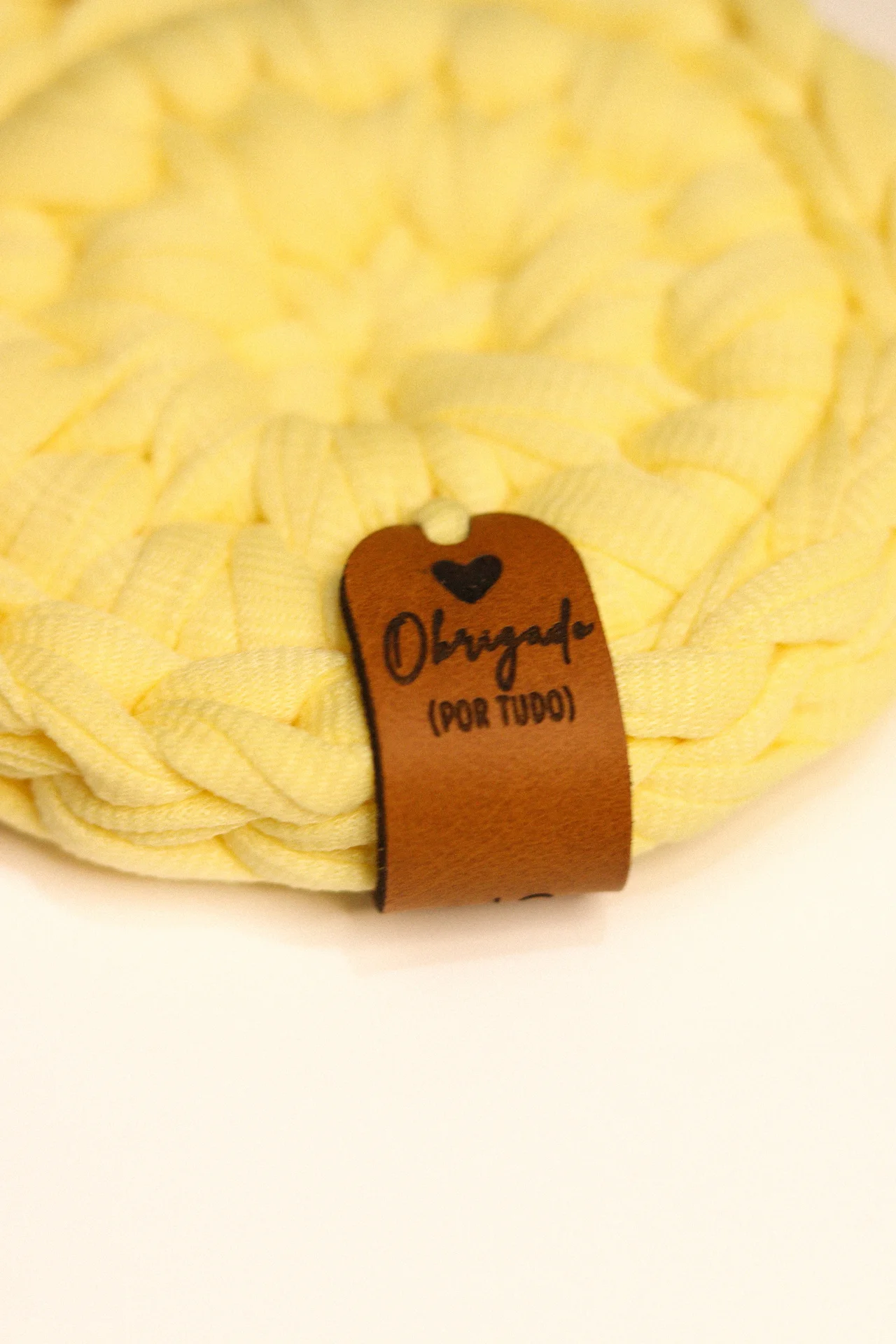Tapete amarelo trançado com etiqueta de couro castanho com texto e coração preto