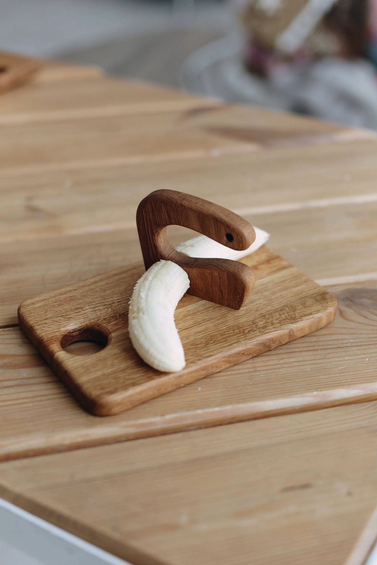 tabua de madeira clara com peça curva e pedaço de banana descascada