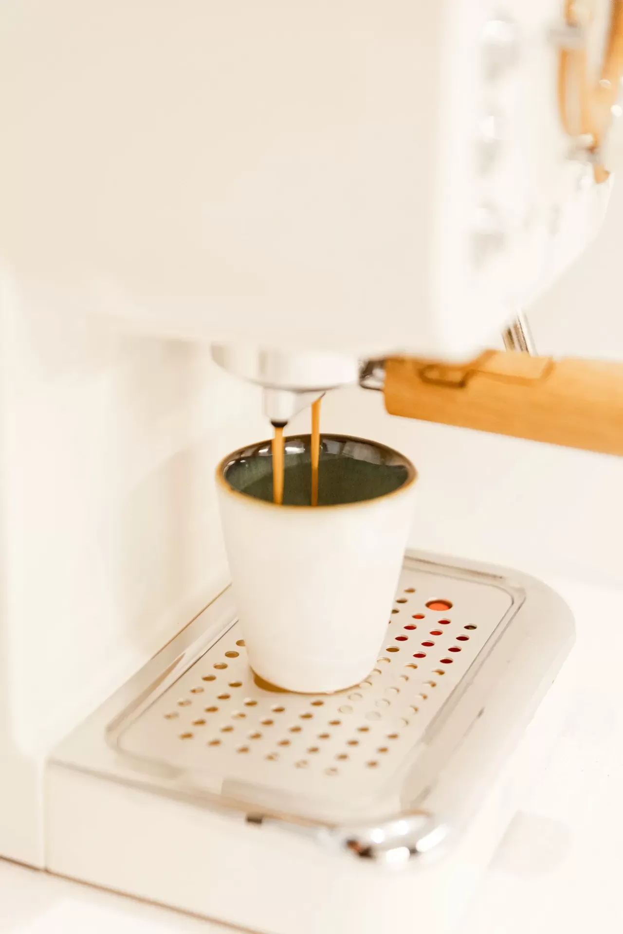 Máquina de café branca a preparar café expresso para chávena branca.