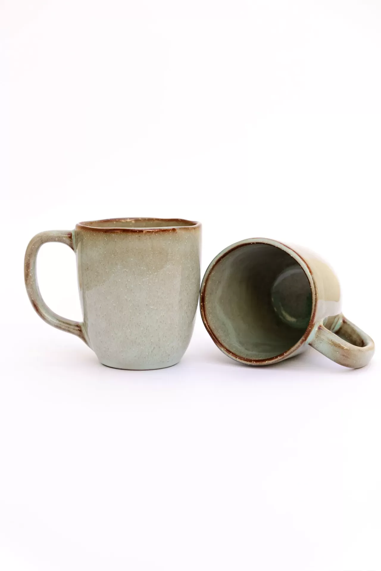 Dois canecas de cerâmica cinza com bordas castanhas, uma em pé e outra deitada