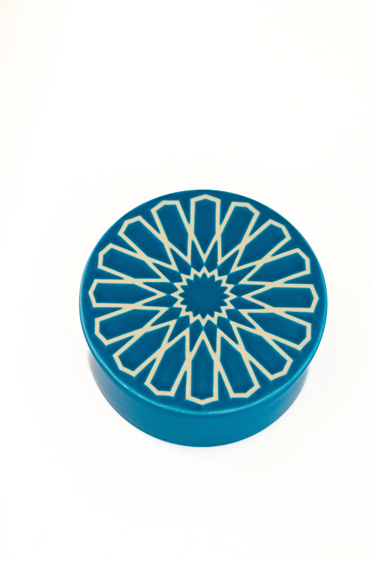 Caixa redonda azul com padrão branco geométrico no topo