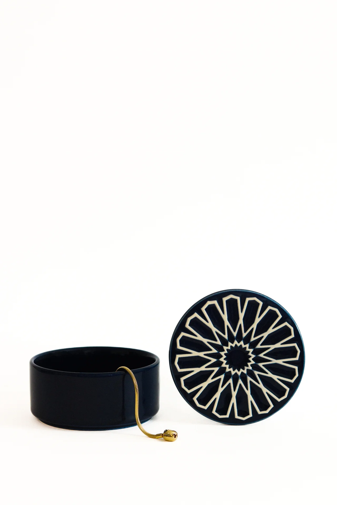 Caixa de cerâmica azul escura com tampa geométrica branca e corrente dourada